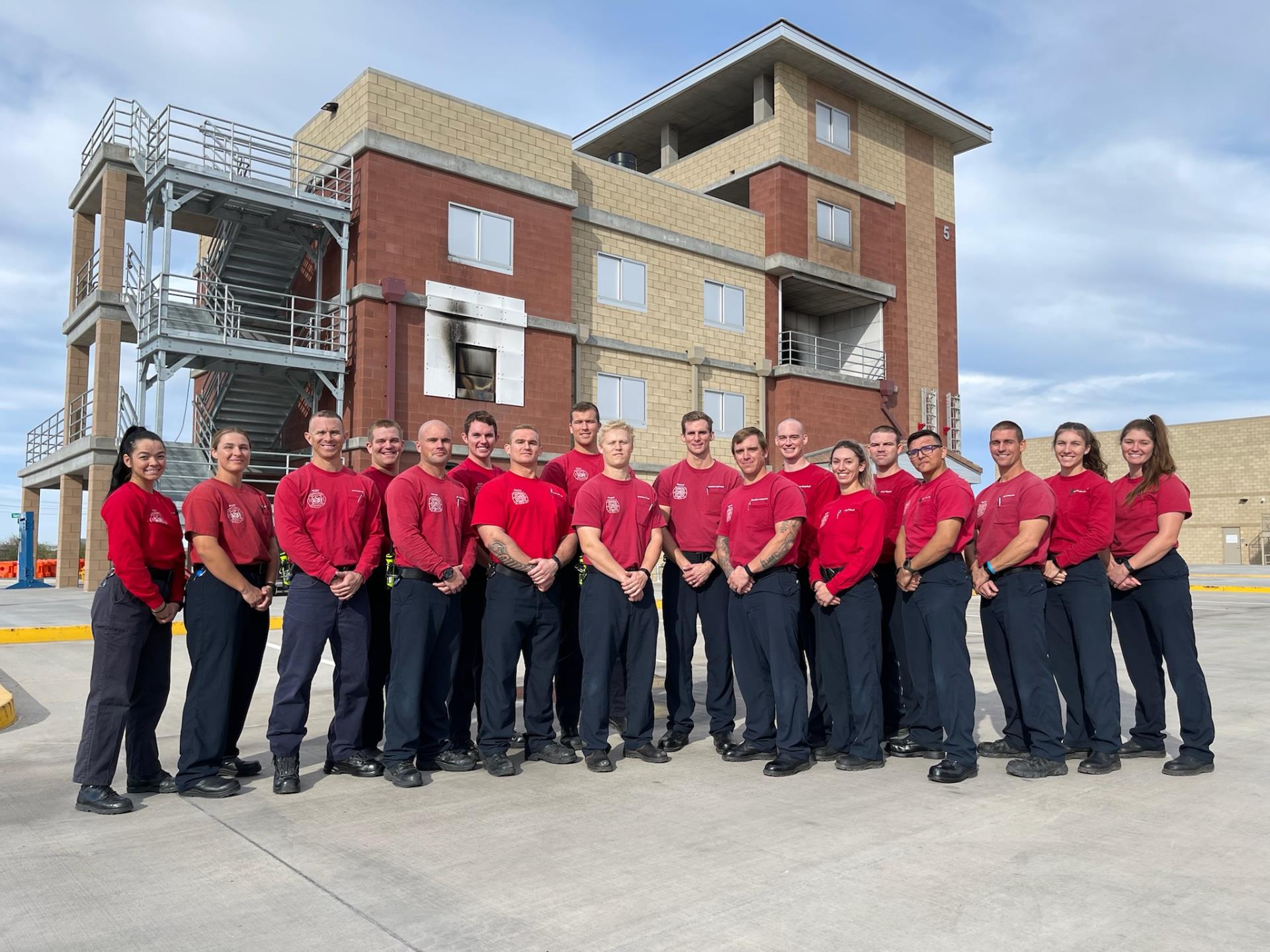 Group of firefighter recruits in front of burn building