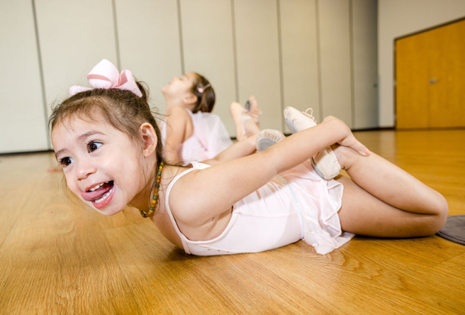 A young ballerina stretches before class. 