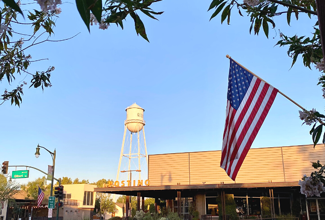 A flag flies in downtown Gilbert as the Water Tower stands tall in the distance.