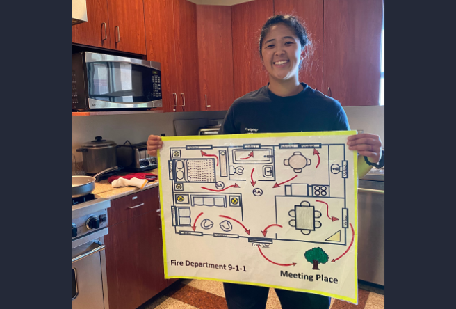 A female firefighter holding a map of a home escape route.