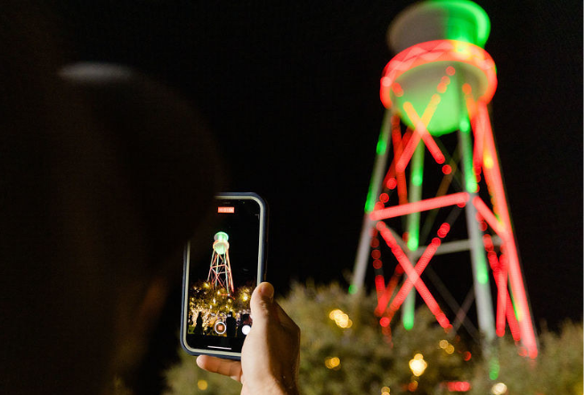 Someone takes a photos on their phone of the Gilbert Water Tower lit for the Holidays.