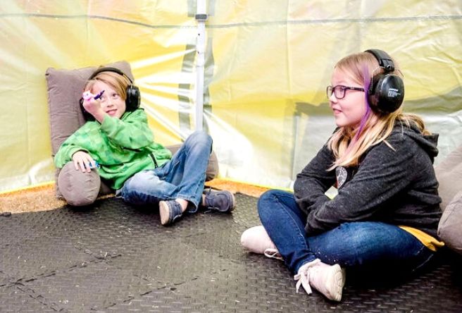 Two children with headphones on take a break in a quiet zone at a Gilbert event.