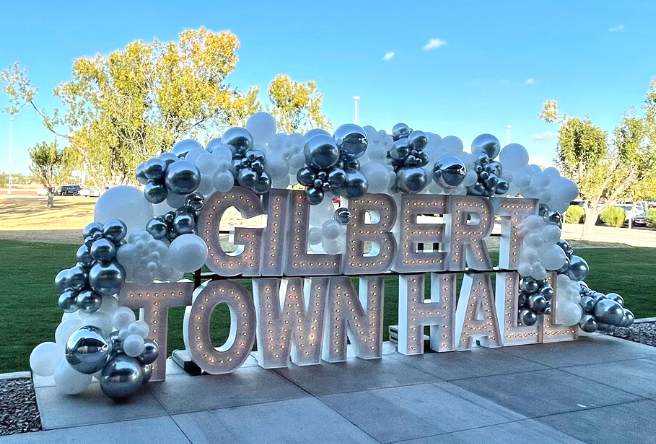 A lighted sign that reads Gilbert Town Hall is covered in balloons at the ribbon-cutting event for the reopening of the building.