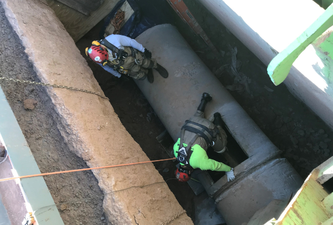 Two workers repairing a water main transmission line.