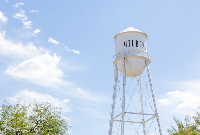 A photo of the Gilbert Water Tower against a blue sky as a few white clouds float by. 