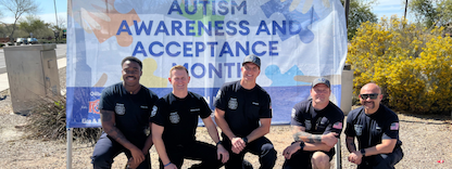 firefighters pose in front of an autism awareness banner