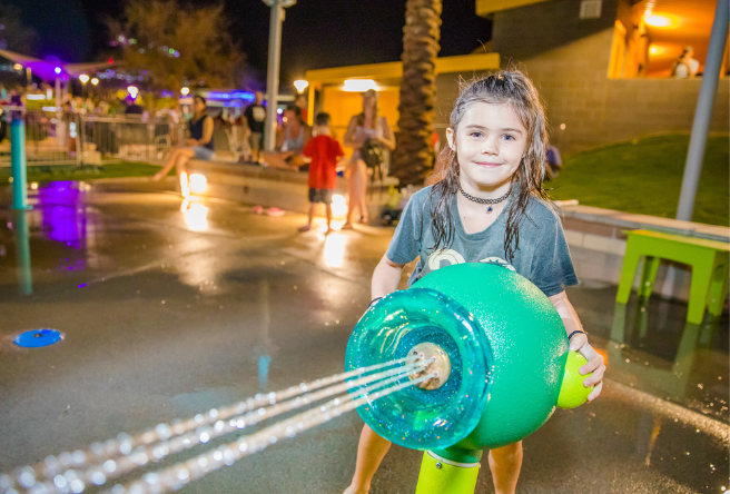 A young park-goer operates one of the large water cannons at Gilbert Regional Park's splash pad.