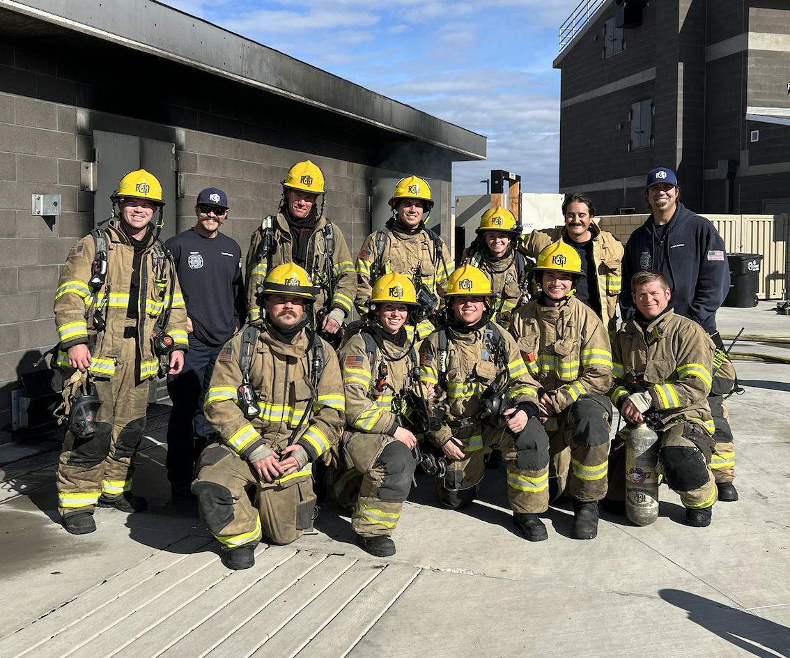 15 firefighters posing for a picture in front of a building