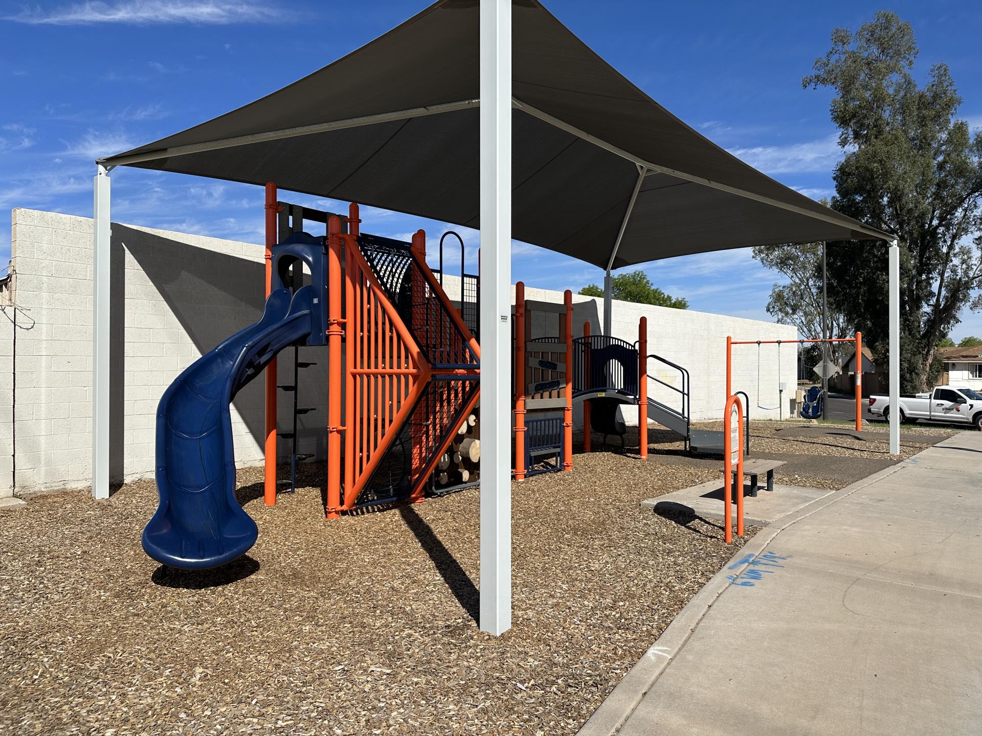 A blue and orange playground with a large shade structure overtop 