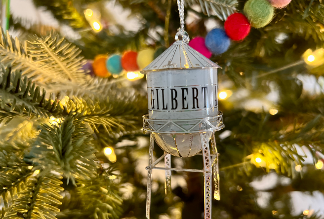 A Gilbert Water Tower ornament hanging from a decorated Christmas Tree.