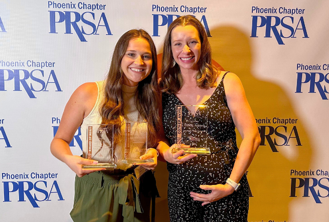 Two female staff members with the Office of Digital Government pose for a photo with their glass trophies.