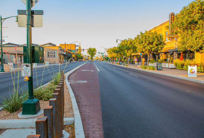 A wide shot of Gilbert Road from the view of the Downtown Heritage district. Street light poles and signs can be seen in the foreground.