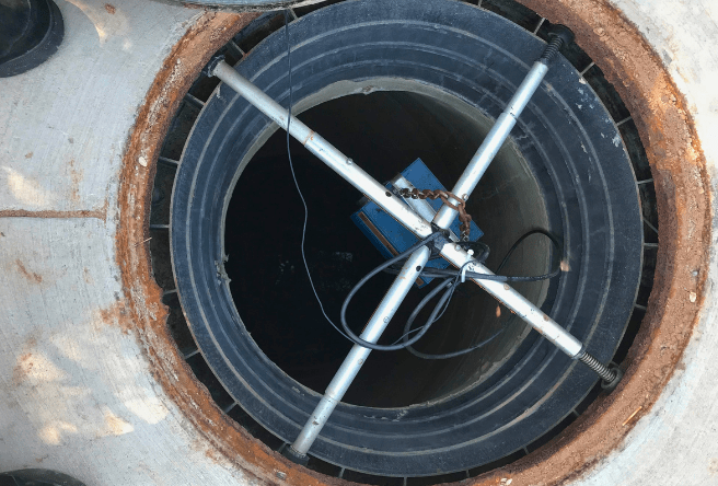 A wide shot of a sewer drain with equipment hanging inside.