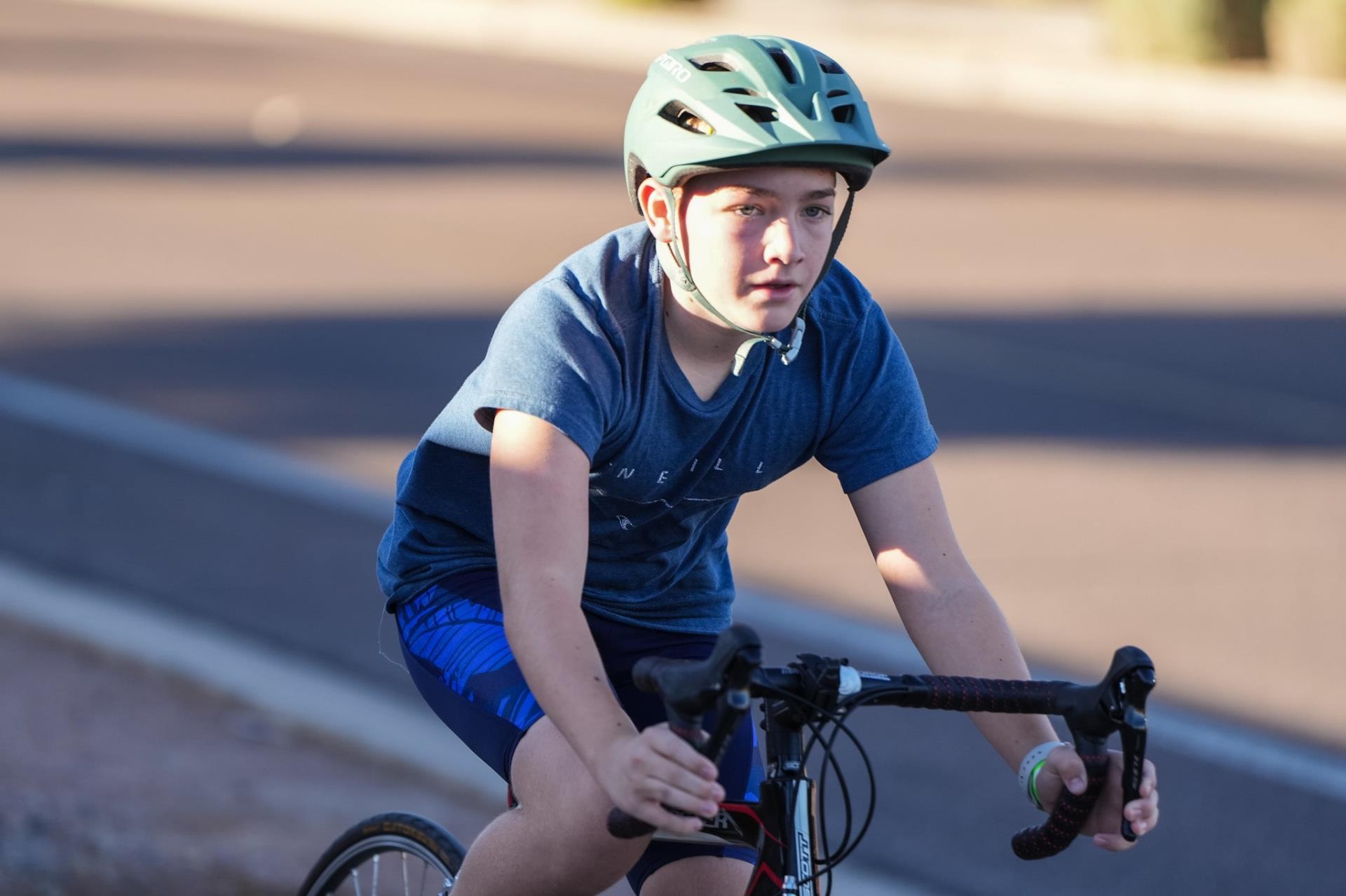 A young boy wearing a helmet rides a bike through a Gilbert street.