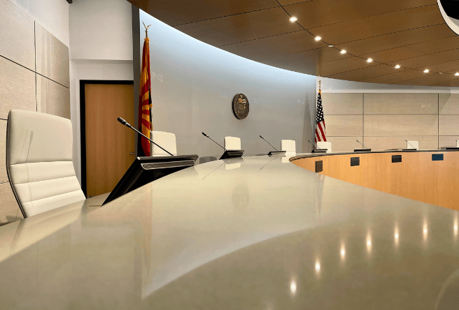 A wide shot of the Gilbert Town Council dais showing council chairs, two flags, and sparkling ceiling lights.