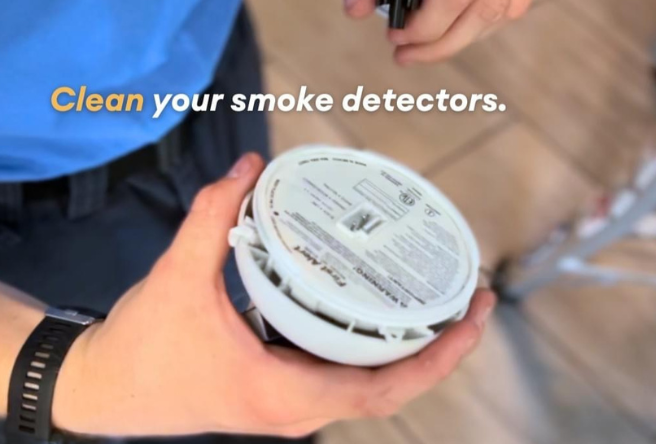 A tight shot of a hand holding a smoke detector with the message above reading, 