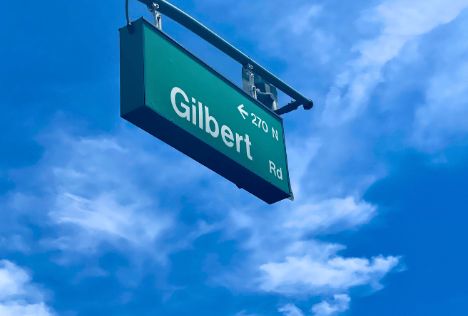 A tight shot of the green Gilbert Street Sign against a blue cloudy sky.