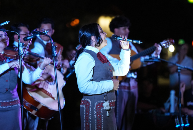 A mariachi band is performing on-stage at night.