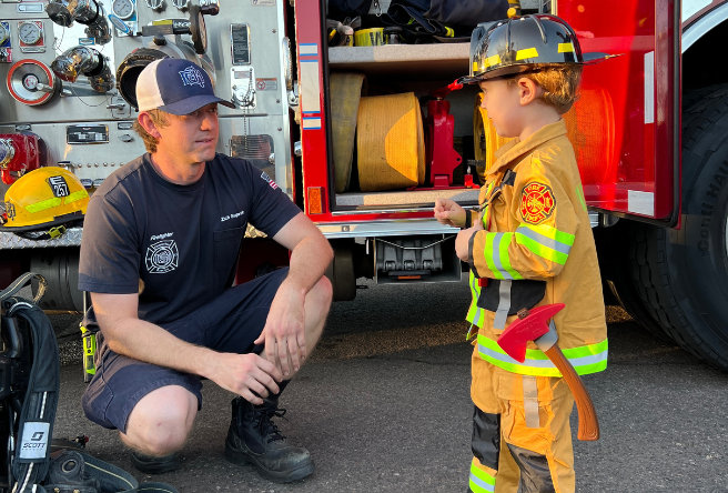 Firefighter smiles at child dressed as firefighter